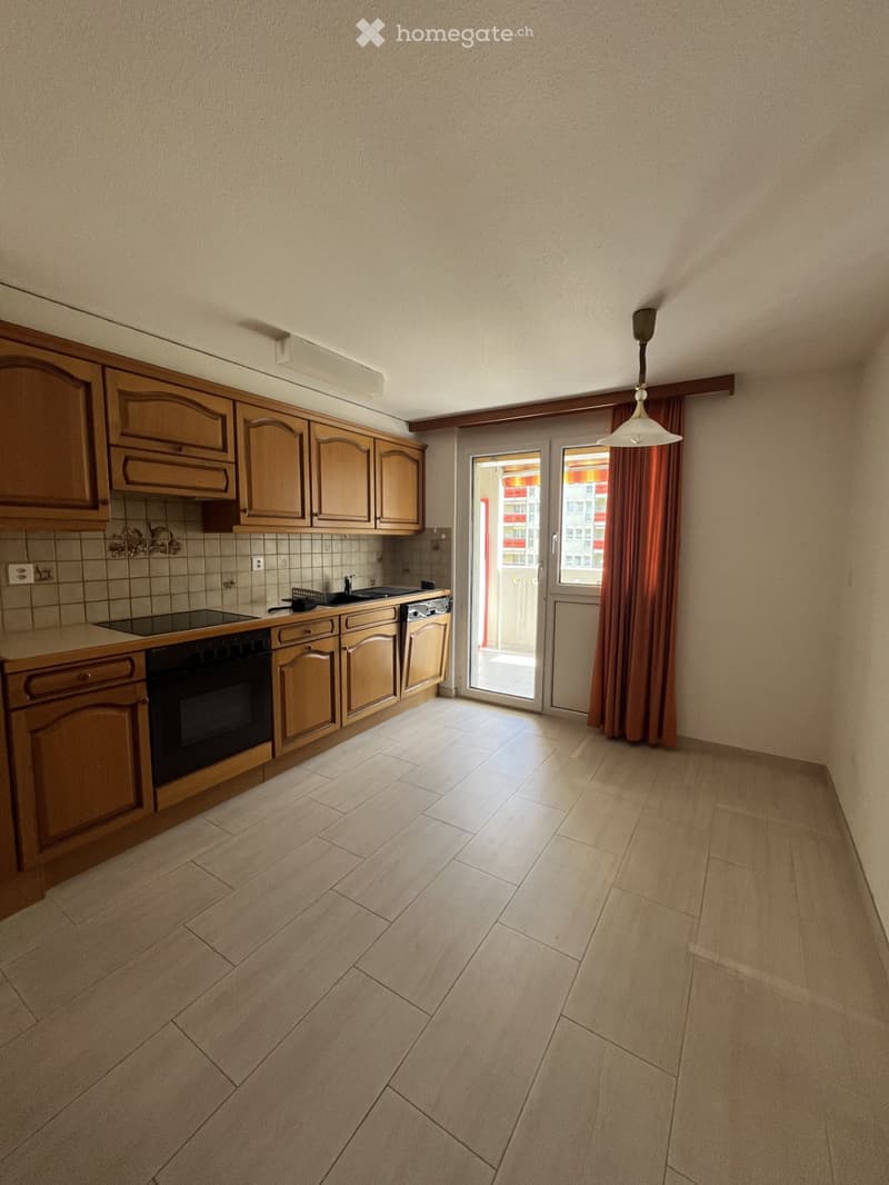 Empty kitchen with wooden cabinets, tiled backsplash, and a view through a glass door to a balcony.