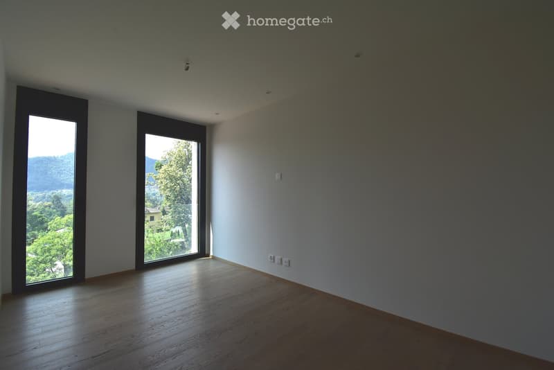 Empty room with wooden flooring, large windows, and neutral-colored walls. No furniture or equipment present.