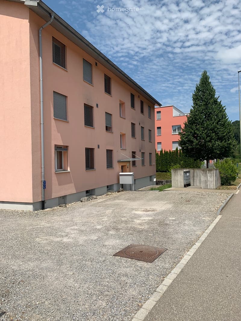 Two-story pink building with multiple windows and a gravel driveway.