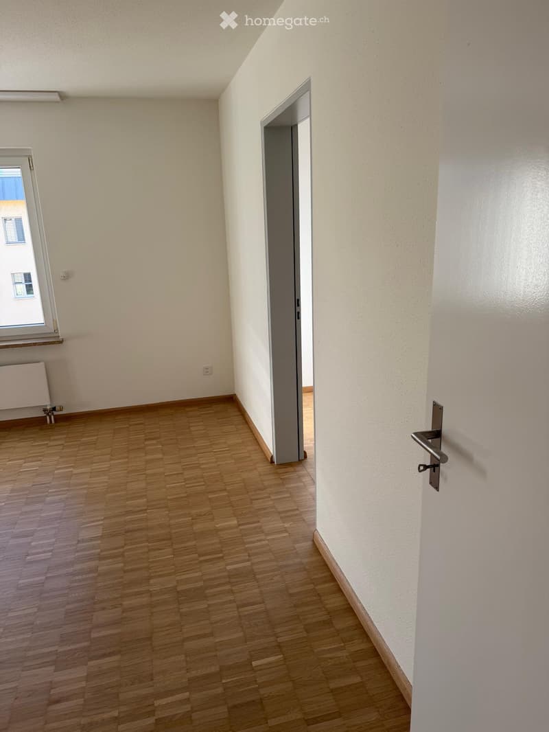Unfurnished Room. Empty hallway with wooden flooring, white walls, and two open doors leading to adjacent rooms.