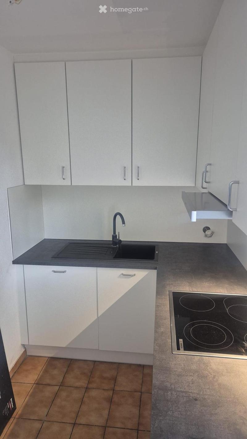 Kitchen. Modern kitchen with white cabinets, a black countertop, a sink with a faucet, and an induction cooktop.