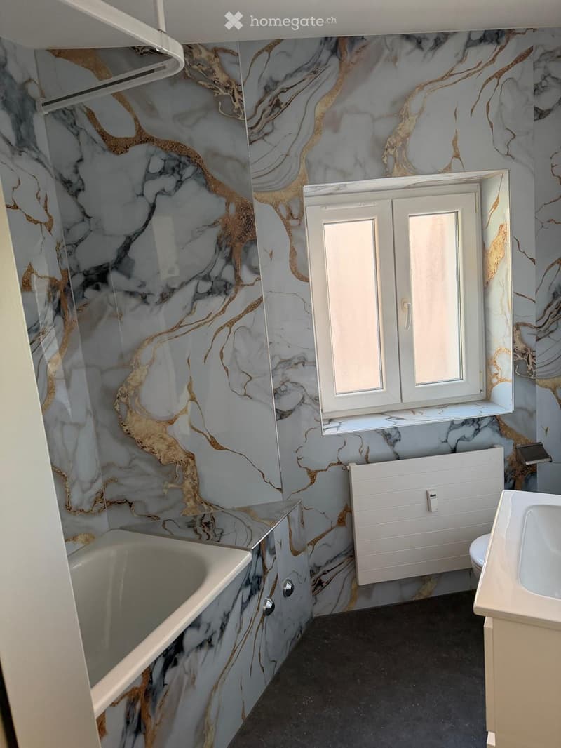 Bathroom. Bathroom with marble-patterned walls, bathtub, toilet, sink, and cabinet.