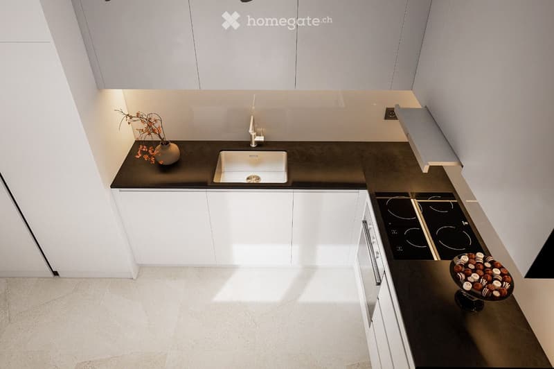 Modern kitchen with white cabinets, black countertops, a sink, induction cooktop, and decorative items including a vase and a bowl of chocolates.