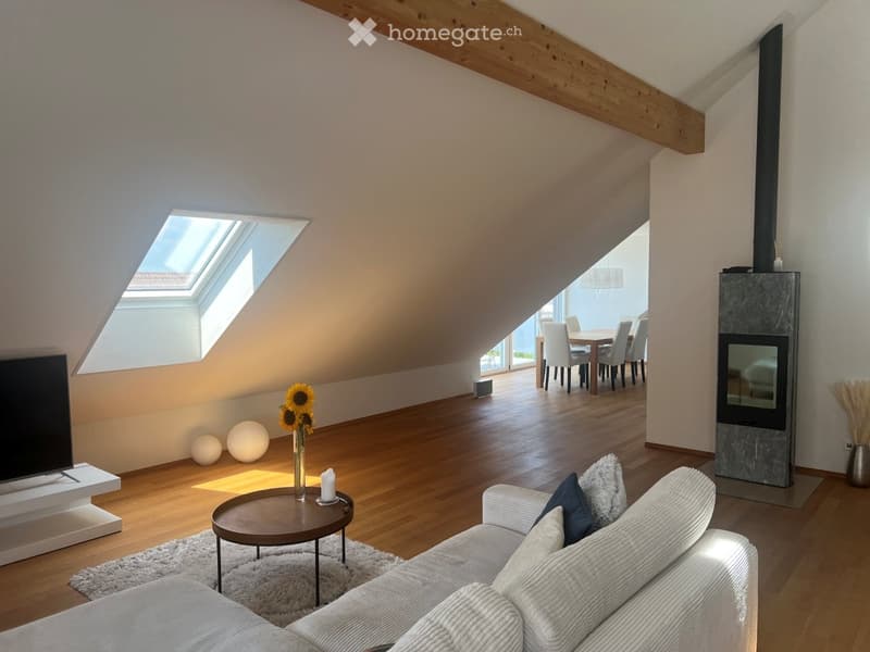 Bright, open living space with wooden floors, a white sofa, coffee table, TV, fireplace, and a dining area with a table and chairs.