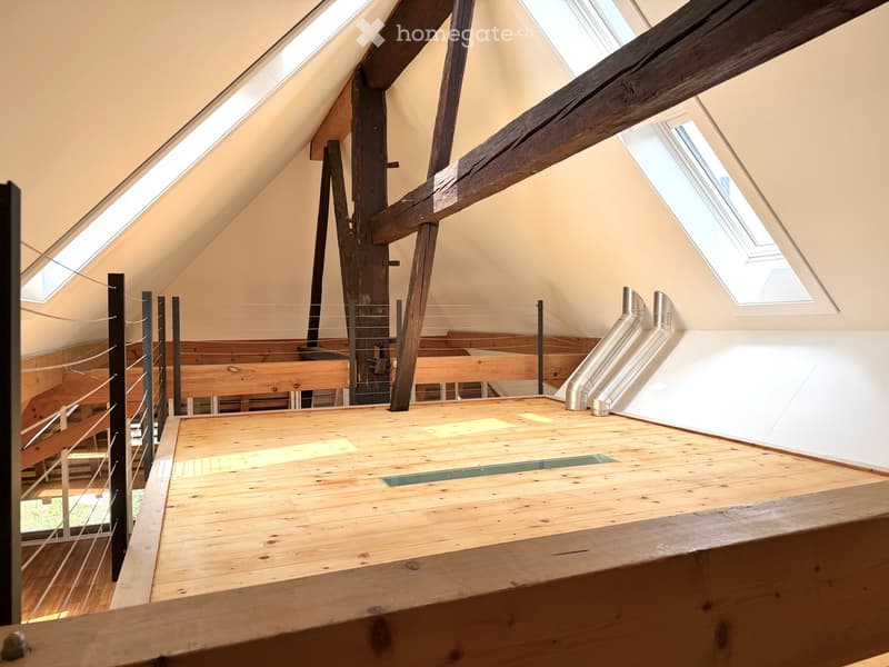 An attic space with wooden floors, exposed wooden beams, skylights, and a metal duct system. The area is unfurnished and appears to be under construction or renovation.