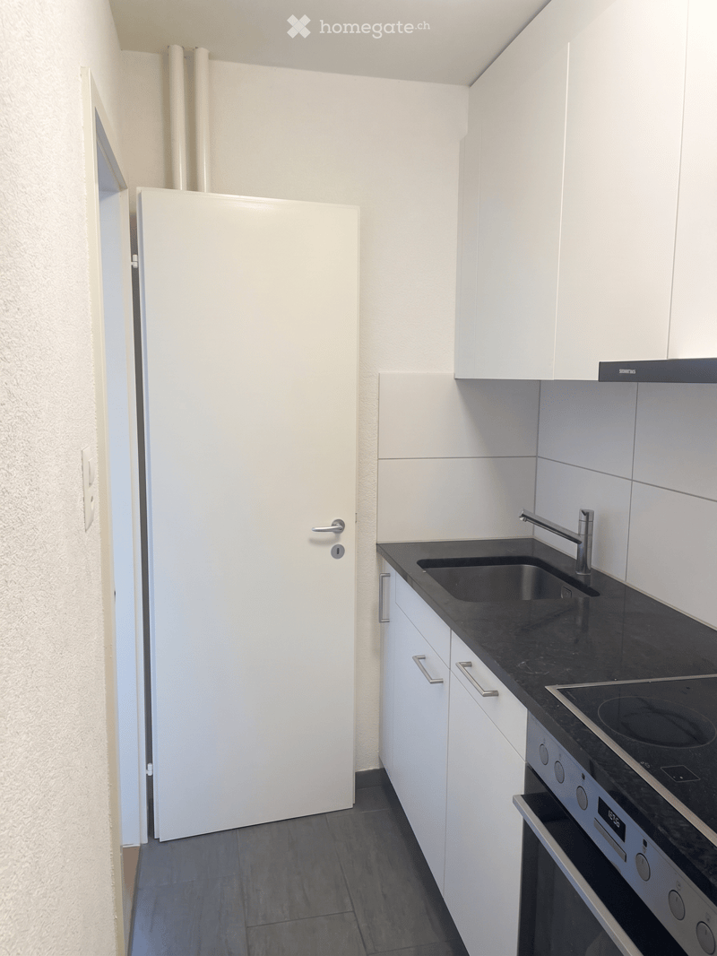 Modern kitchen with white cabinets, black countertops, stainless steel sink, and built-in appliances.