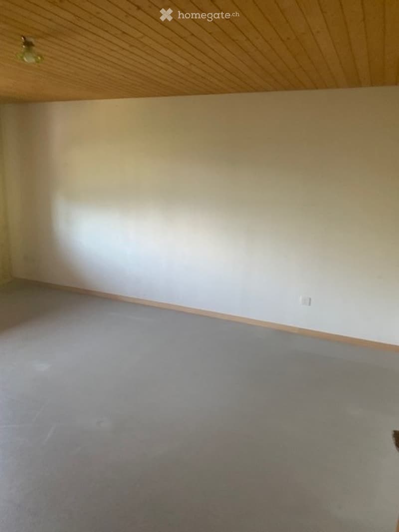 Empty room with light-colored walls, wooden trim, and carpeted floor. No furniture or equipment visible.