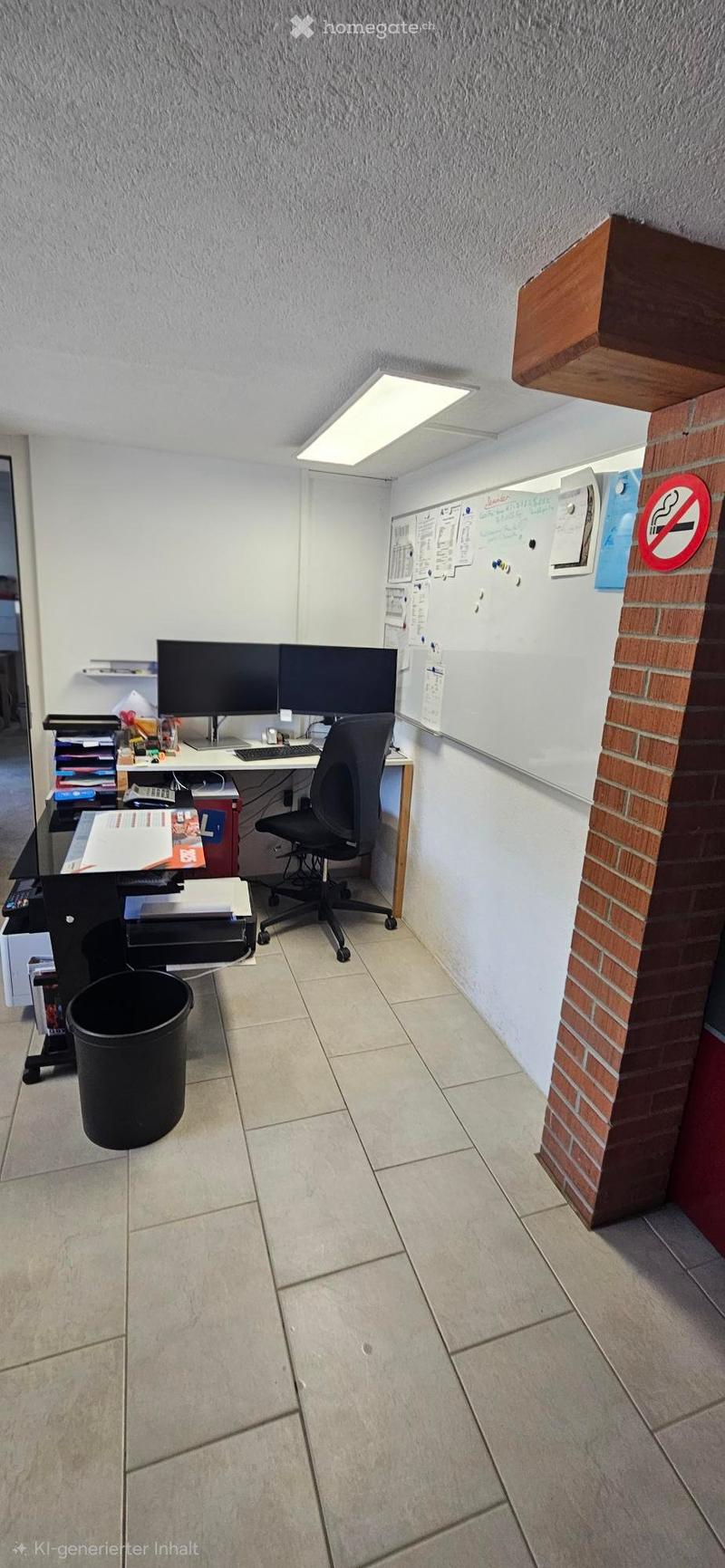 Office space with a desk, two monitors, a chair, a printer, and a trash bin. The room has tiled flooring and white walls.