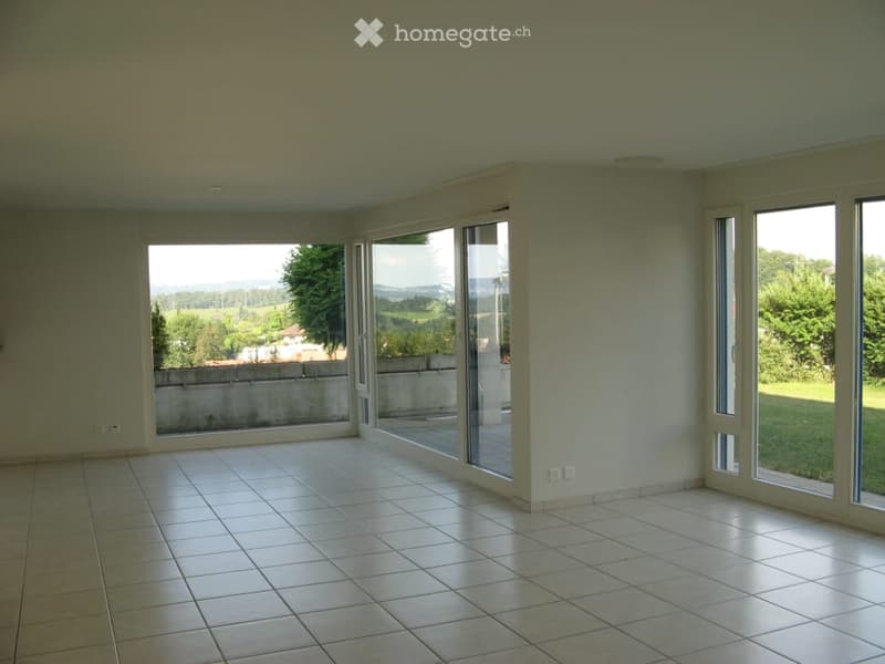 Empty room with white tiled flooring, large windows, and sliding glass doors leading to an outdoor area.