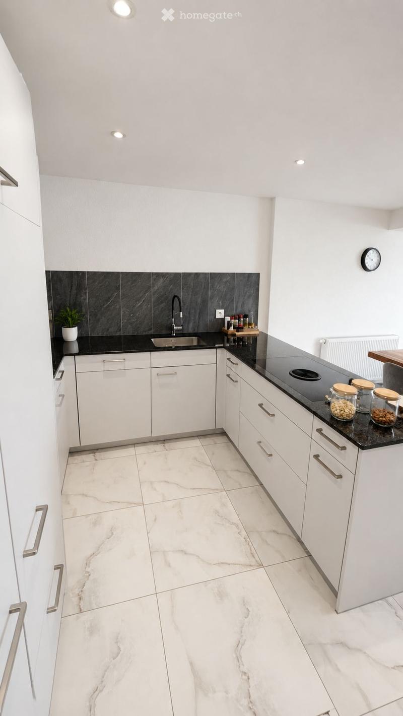 Modern kitchen with white cabinets, marble flooring, black countertop, sink, and small decorative jars on the counter.