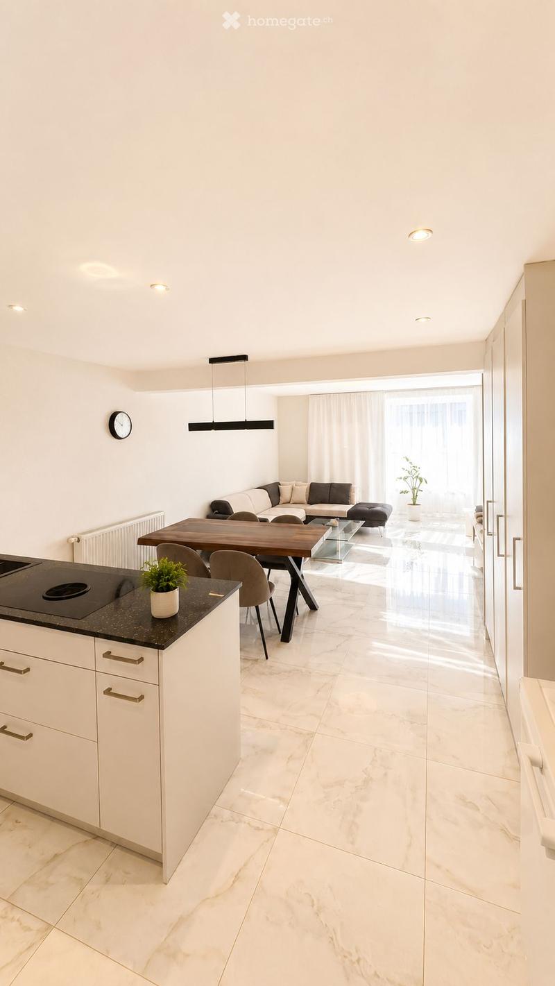 Modern open-plan living and dining area with white walls, marble flooring, and integrated kitchen. Features a sofa, coffee table, ottoman, dining table with chairs, and a kitchen island with a potted plant.