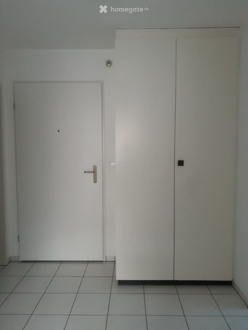 Empty room with tiled floor, two white doors, and light grey walls.
