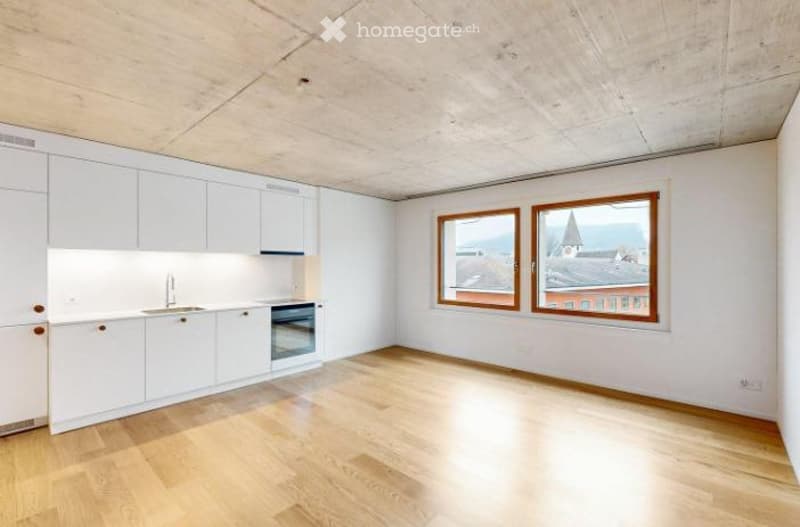 Bright, modern kitchen with white cabinets, wooden flooring, and large windows offering a city view.