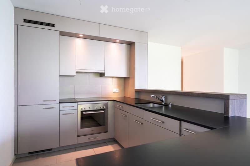 Modern kitchen with white cabinets, stainless steel oven, black countertop, and a sink with a faucet.