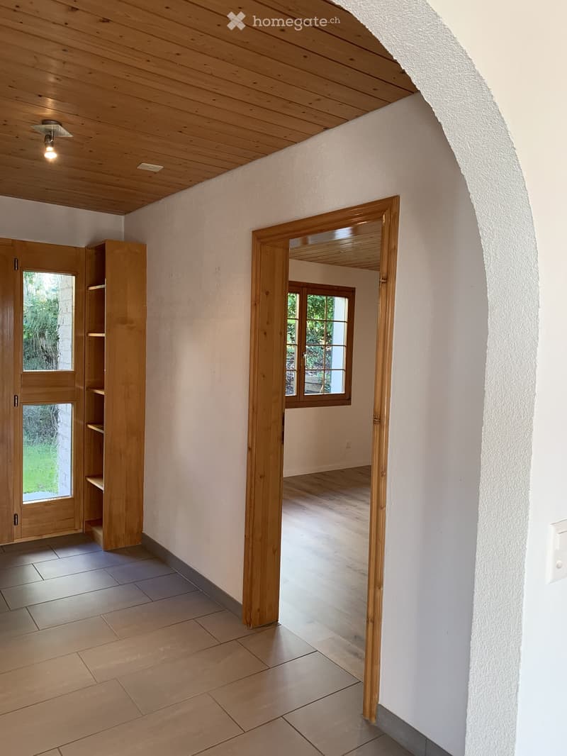 Empty hallway with wooden ceiling, tiled floor, and open wooden doors leading to other rooms.