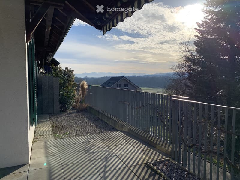 Balcony with metal railing, tiled floor, and scenic view of mountains and countryside.