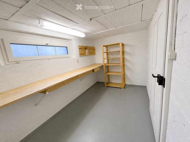 Minimalist room with white brick walls, grey floor, a long wooden table, and a wooden shelf.