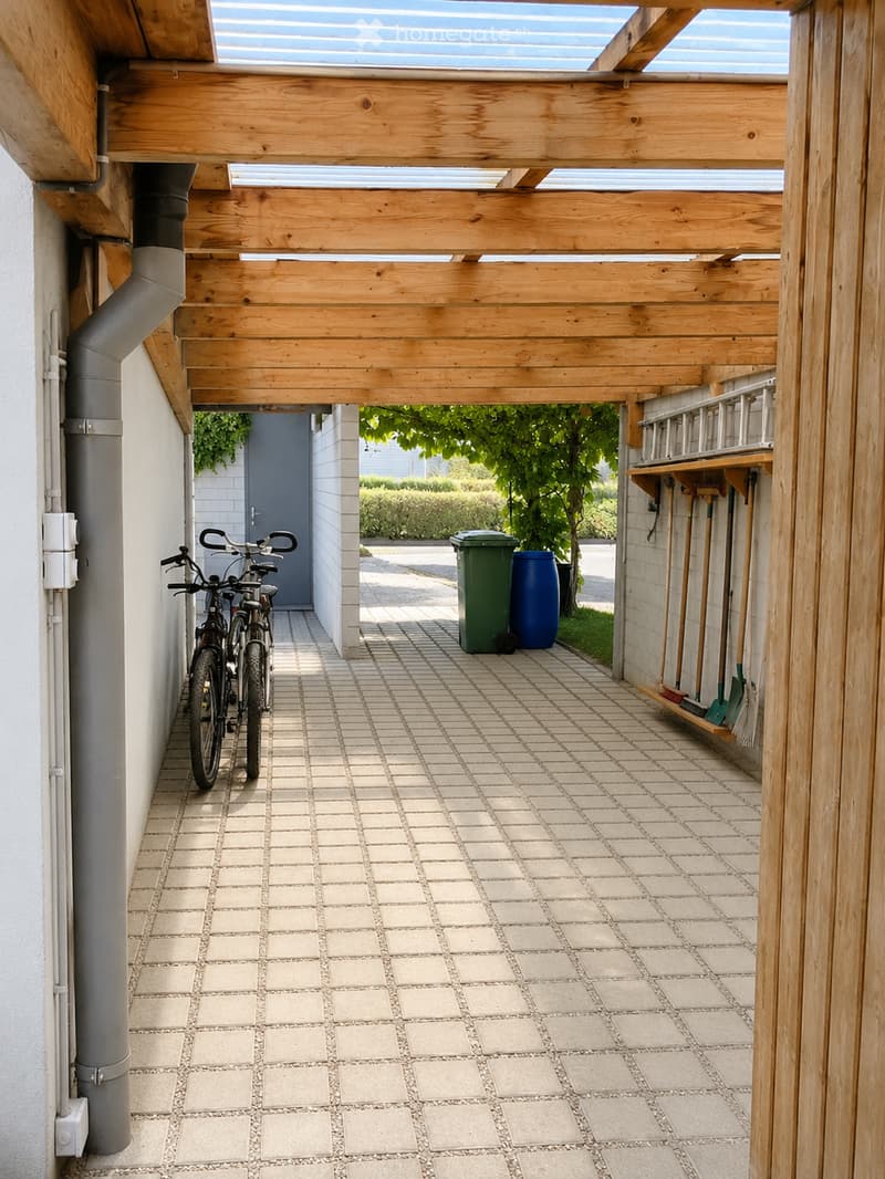 A covered outdoor area with tiled flooring, bicycles, trash bins, and garden tools stored on a wooden shelf.