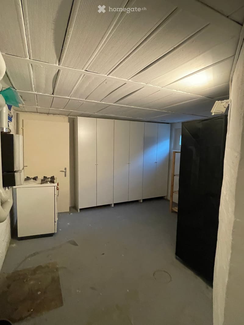 Empty room with white cabinets, a small sink, and a partially visible doorway leading to another space. The floor shows some stains and wear.