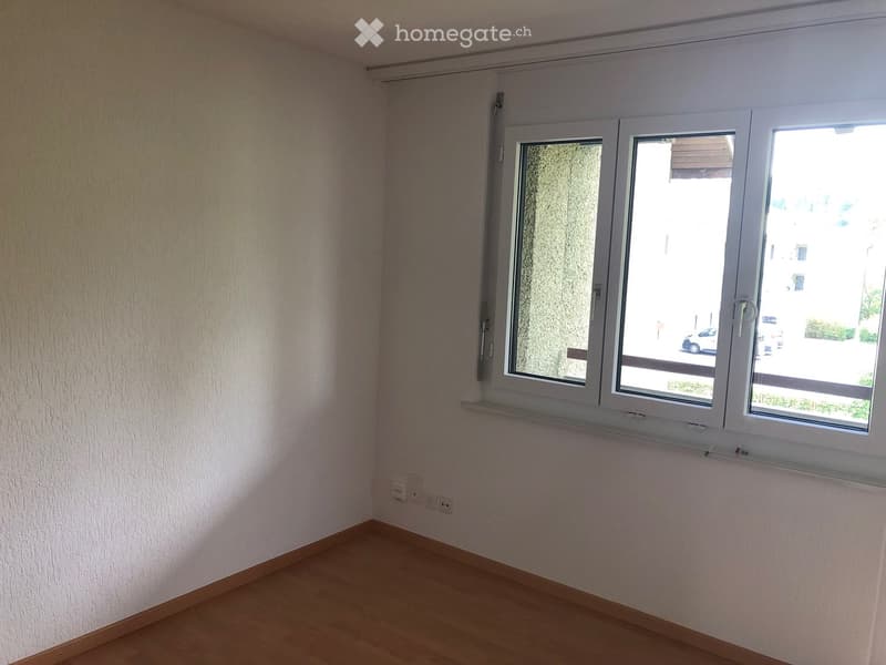Empty room with light-colored walls, wooden flooring, and large windows with white frames. No furniture or equipment is present.