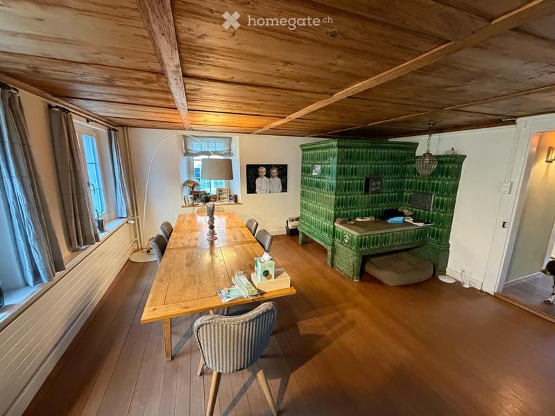 Dining room with wooden table, chairs, green cabinet, floor lamp, and picture on wall.