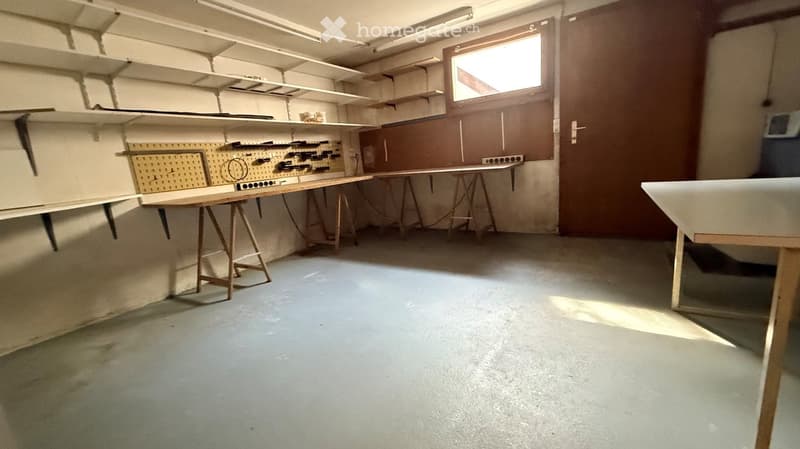 Empty room with concrete floor, white walls, and wooden tables with shelves. No furniture or equipment.