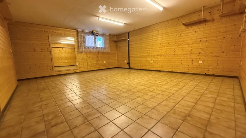 Empty room with wooden walls, tiled floor, and a large mirror on one wall. No furniture or equipment is present.