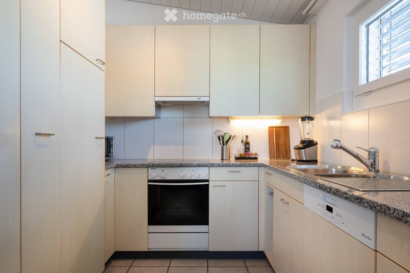 Modern kitchen with white cabinets, granite countertop, stainless steel sink, oven, and various appliances.