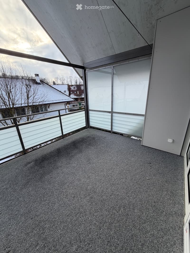 Balcony with gray carpet, large glass windows, railings