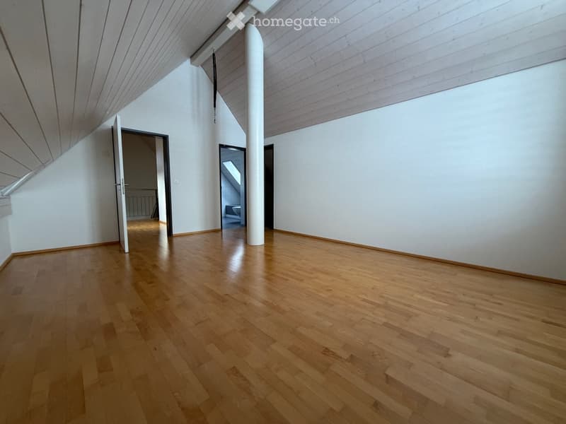empty attic room with wooden floors, white walls, two doors, slanted ceiling