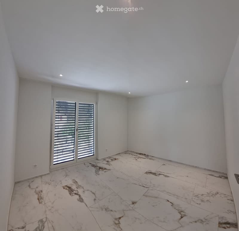 Empty room with white walls, marble flooring, and large sliding glass doors with blinds.