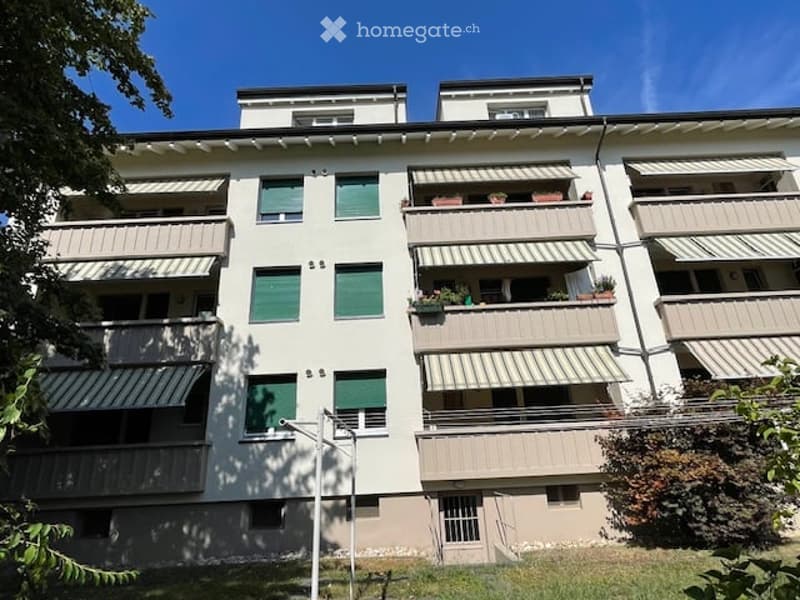 Multi-story residential building with multiple balconies, green shutters, and decorative railings.