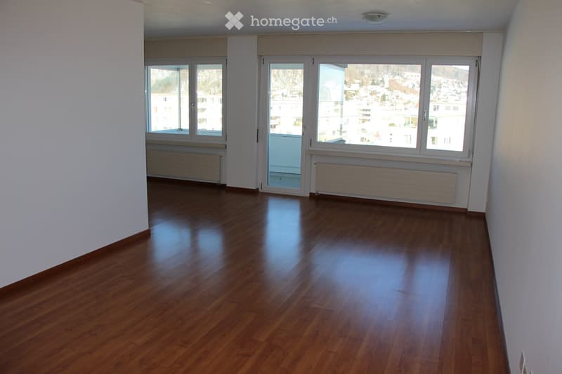 Empty room with wooden flooring, white walls, large windows, and radiators. No furniture or equipment present.