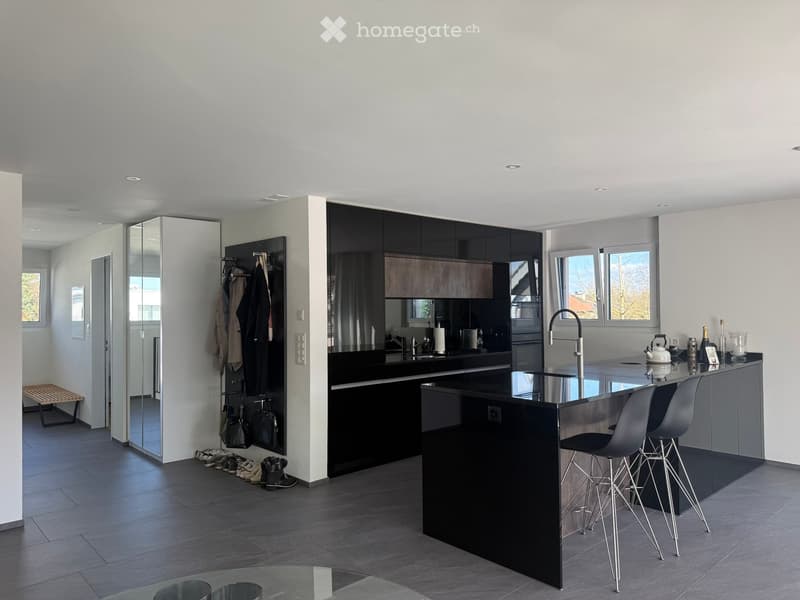 modern kitchen with black countertops, island with stools, large windows, walk-in closet, tiled floor