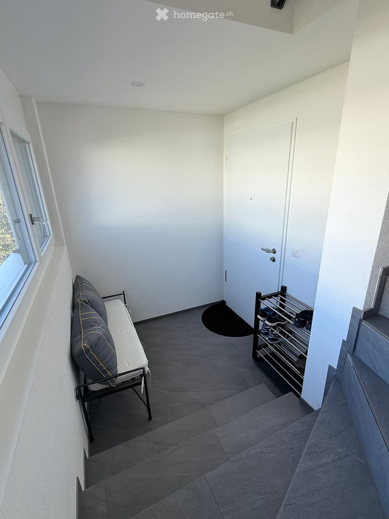 Empty room with a bench, a shoe rack, and a window