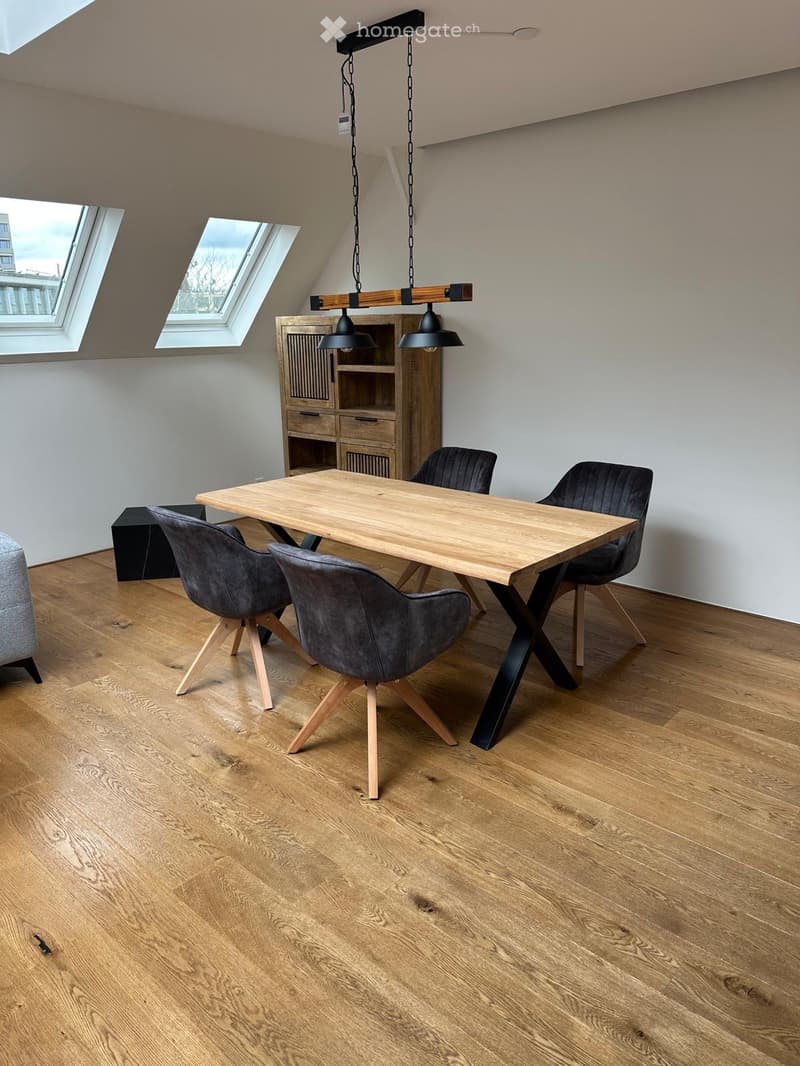 Modern dining area with a wooden dining table, four grey chairs, a wooden cabinet, and pendant lights hanging from the ceiling.