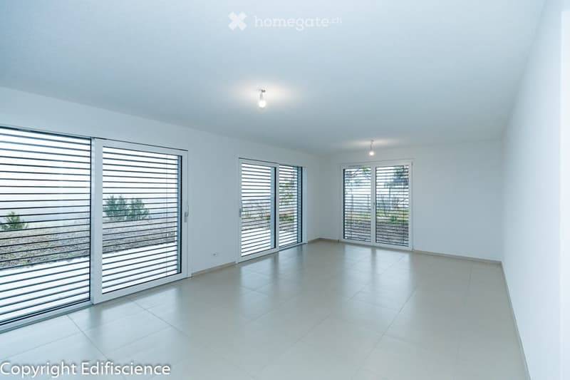 Completely empty room with white walls, tiled floor, and large sliding glass doors leading to an outdoor area.