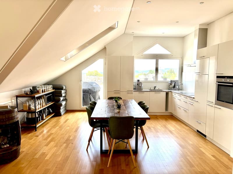 Bright, modern kitchen and dining area with wooden flooring, white cabinets, and large windows offering a scenic view. Includes a dining table with chairs, a microwave, and various kitchen appliances.
