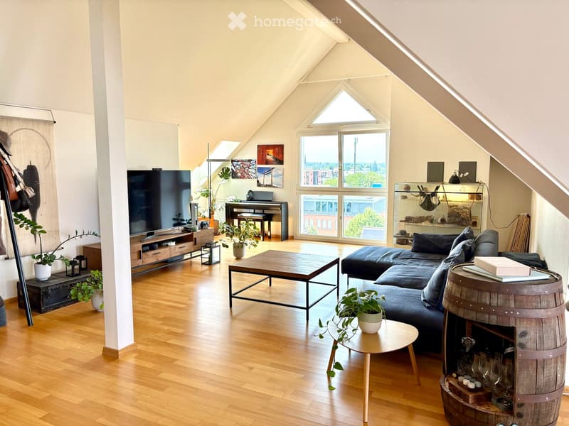 Bright living room with wooden flooring, large windows, a sectional sofa, coffee table, TV stand, piano, and decorative plants.
