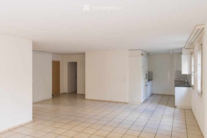 Empty kitchen with tiled floor, white cabinets, and a sink area. No furniture or appliances are present.