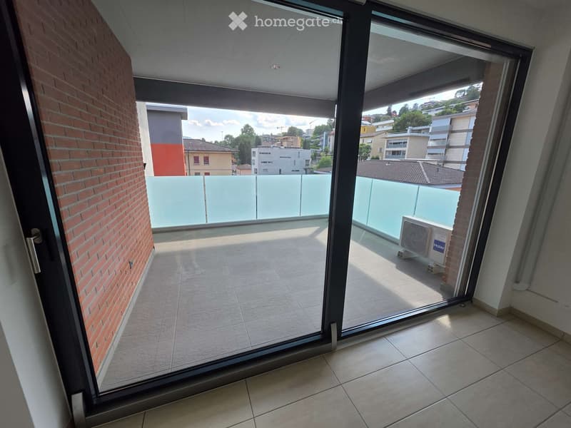 Balcony with tiled floor, glass railing, and an air conditioner unit visible on the balcony.