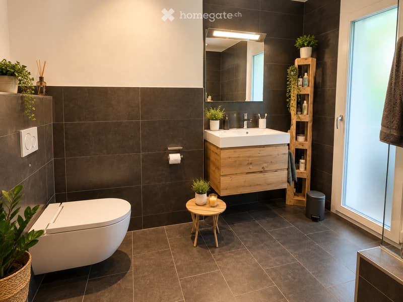 Modern bathroom with dark tiled walls, a white sink with wooden cabinet, a toilet, a small wooden stool with a candle, and a wooden shelf with plants and toiletries.