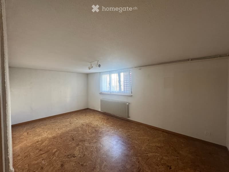 Empty room with wooden flooring, white walls, a window with blinds, and a radiator. No furniture or equipment present.