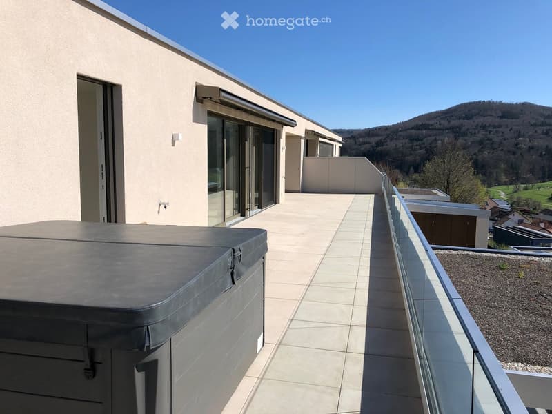 Modern rooftop terrace with tiled flooring, glass railing, and scenic mountain view. Features a covered hot tub on the left side.