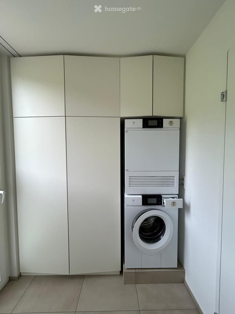 A small, clean bathroom with a white washing machine and matching cabinets.
