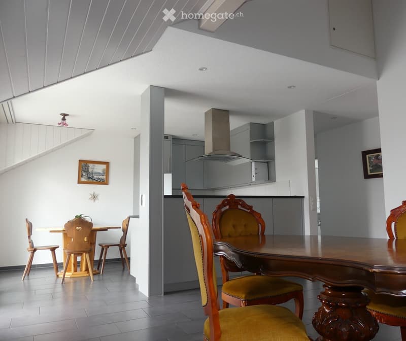 Open-plan living and dining area with modern kitchen, dining table with chairs, and decorative picture frame on wall.