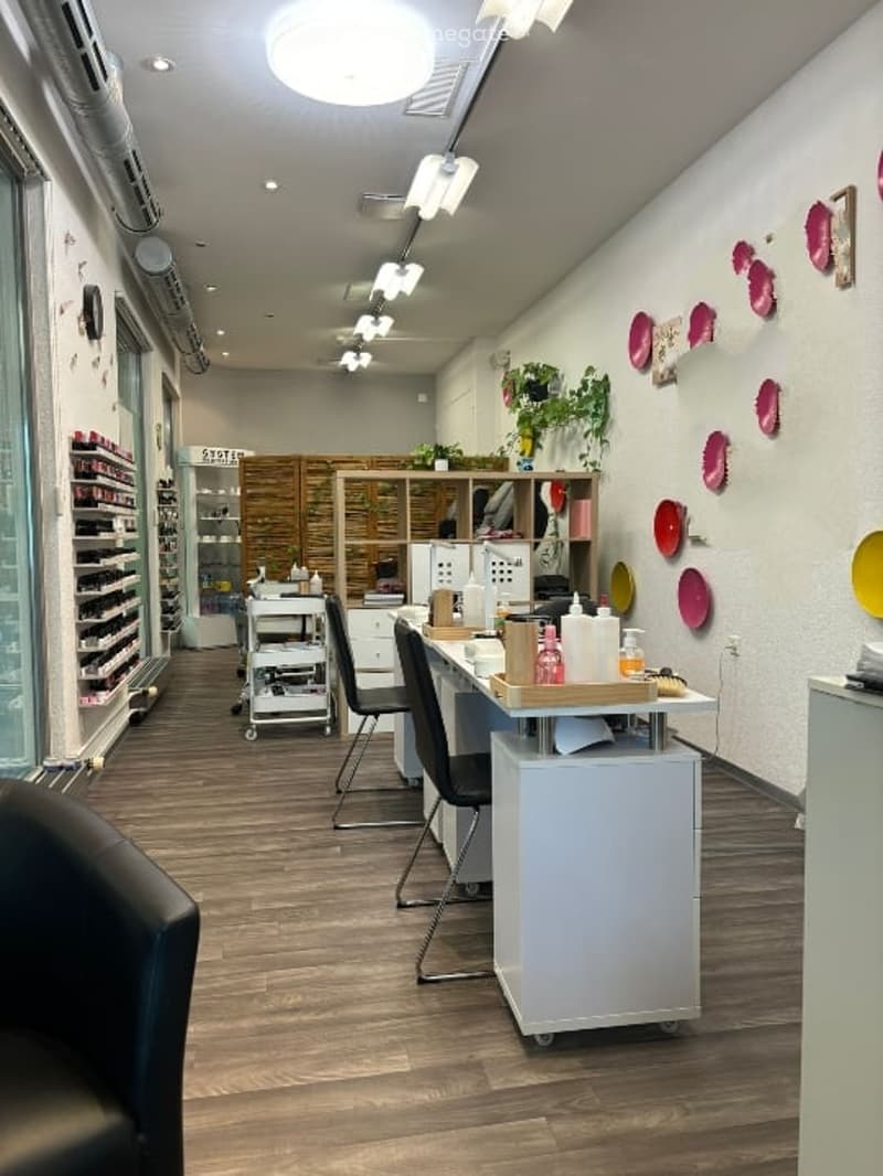 Interior of a salon with tables, shelves, a desk, a glass door, and decorative plates on the wall.