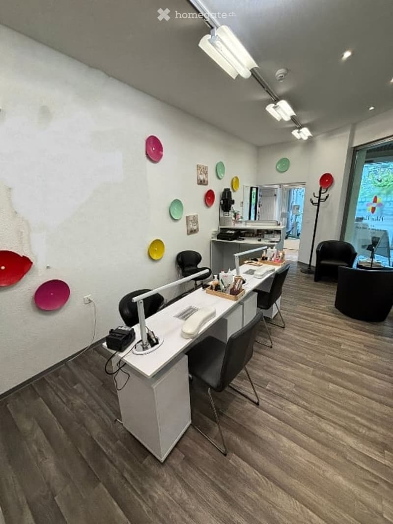 Salon, wooden floor, modern white desk, chairs, bright ceiling lamps, colorful decorative plates on the wall