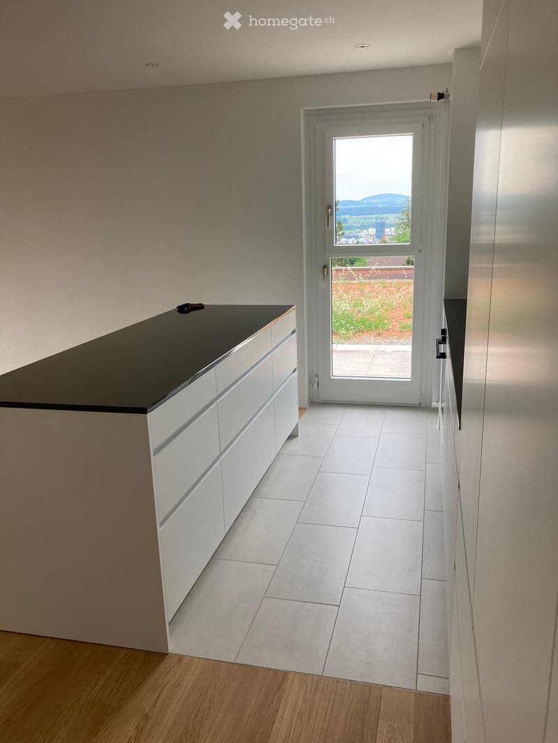 Modern hallway with white tiled floor, white cabinetry, and a large glass door leading to an outdoor area with a view of mountains.