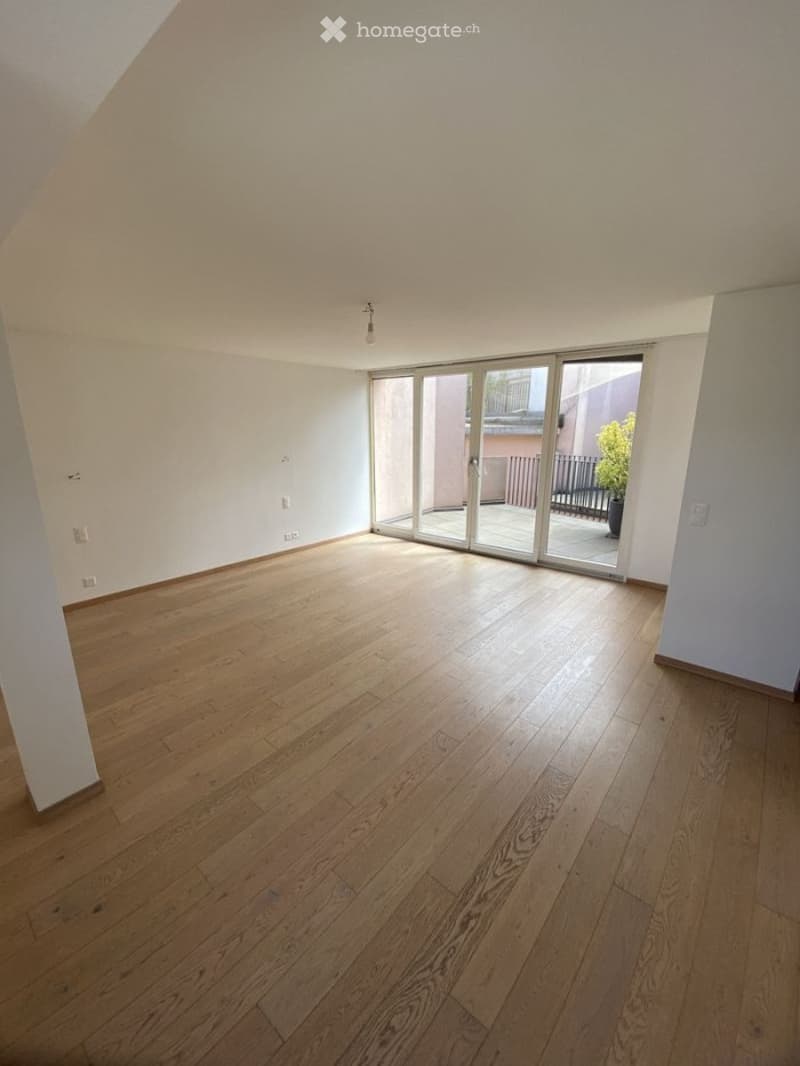 Empty room with wooden flooring, white walls, and large sliding glass doors leading to a balcony.